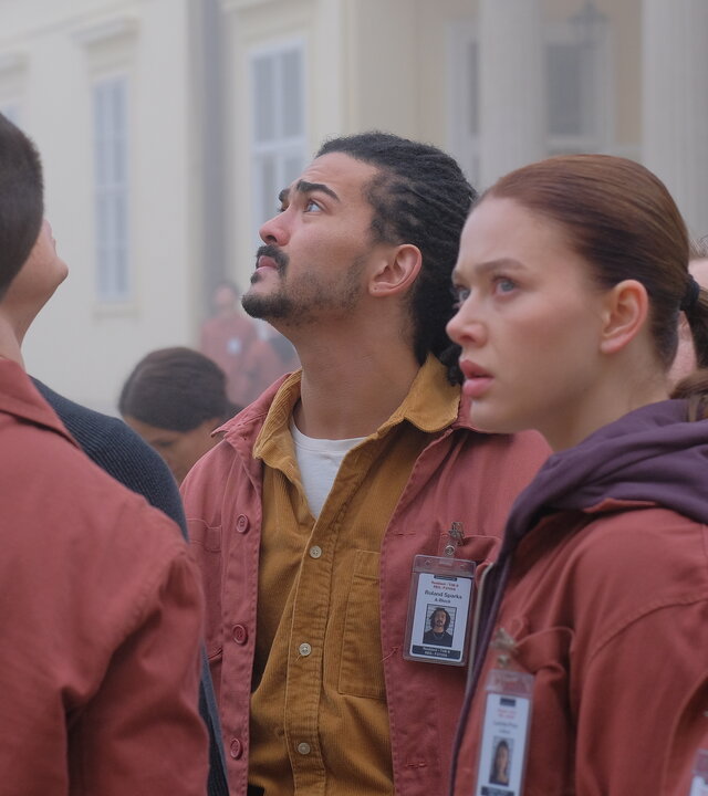 "Fallen - Schatten": Daniel (Gijs Blom), Roland (Lawrence Walker), Luce (Jessica Alexander) und Gabbe (Indeyarna Donaldson-Holness) blicken angespannt nach oben. Im Hintergrund ist ein helles Gebäude im dichten Nebel zu erkennen.