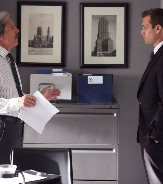 "Suits - Zweifelhafte Absichten": Harvey (Gabriel Macht) steht in einem hellen, modern eingerichteten Büro und blickt Cameron Dennis (Gary Cole) ernst an. Cameron hält ein Papier in der Hand und scheint im Gespräch mit Harvey zu argumentieren.