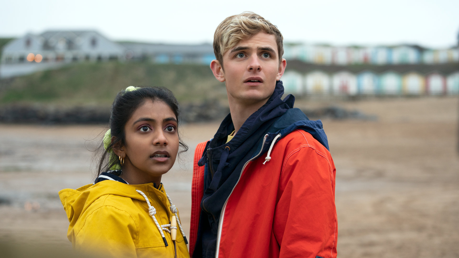"Alex Rider - Surfen": Alex (Otto Farrant) und Sabina (Charithra Chandran) stehen gemeinsam an einem Strand und schauen verstört in die Ferne.