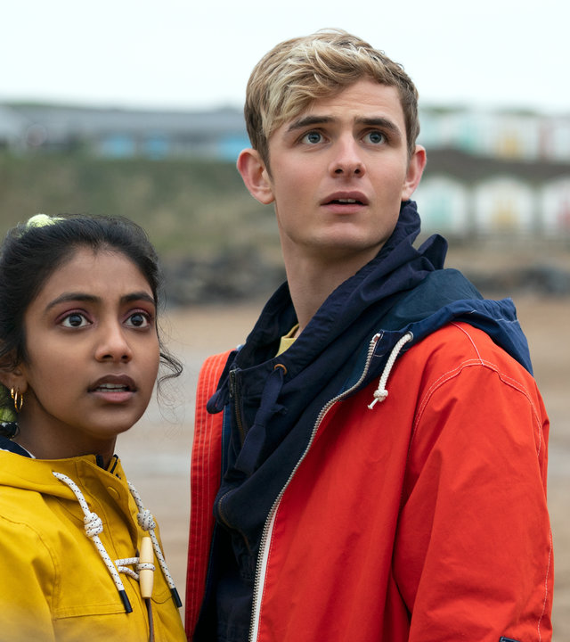 "Alex Rider - Surfen": Alex (Otto Farrant) und Sabina (Charithra Chandran) stehen gemeinsam an einem Strand und schauen verstört in die Ferne.