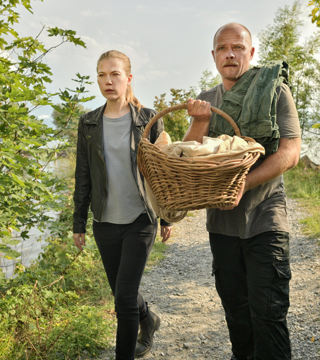 "Die Toten vom Bodensee - Der Seelenreis": Hannah Zeiler (Nora Waldstätten) und Micha Oberländer (Matthias Koeberlin) laufen nebeneinander über eine Wiese. Micha Oberländer (Matthias Koeberlin) hält einen Korb in der Hand.
