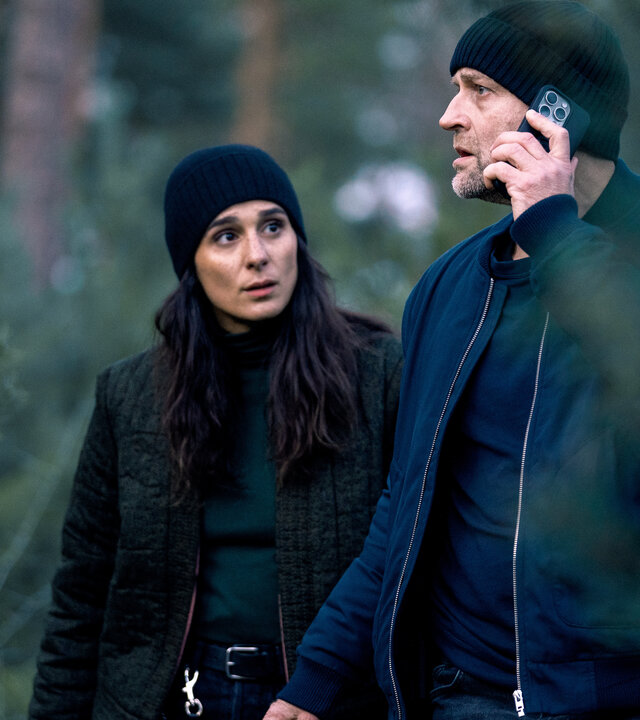 "Jenseits der Spree - Tod in der Königsheide": Mavi (Aybi Era) und Robert (Jürgen Vogel) stehen im Wald. Robert telefoniert mit seinem Mobiltelefon und schaut besorgt zur Seite. Mavi schaut Robert erwartungsvoll an.