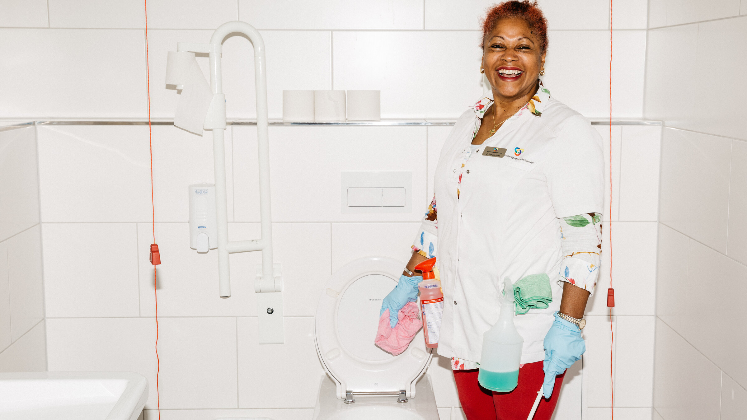 "Euer Schmutz ist unser Job - Reinigungskräfte im Einsatz": Jenny steht vor einer Toilette, blickt in die Kamera. In einer Hand hält sie ein Putztuch in der anderen eine Toilettenbürste.