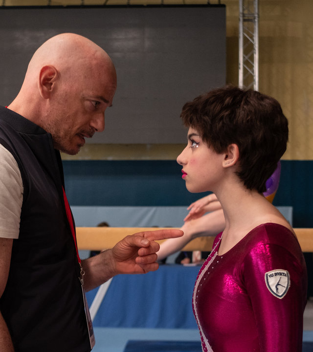"The Gymnasts: Freitag": Mannschaftsarzt Alex (Filippo Nigro) redet vor den Wettkämpfen in der Sporthalle auf die Turnerin Martina (Alessia De Falco) ein.