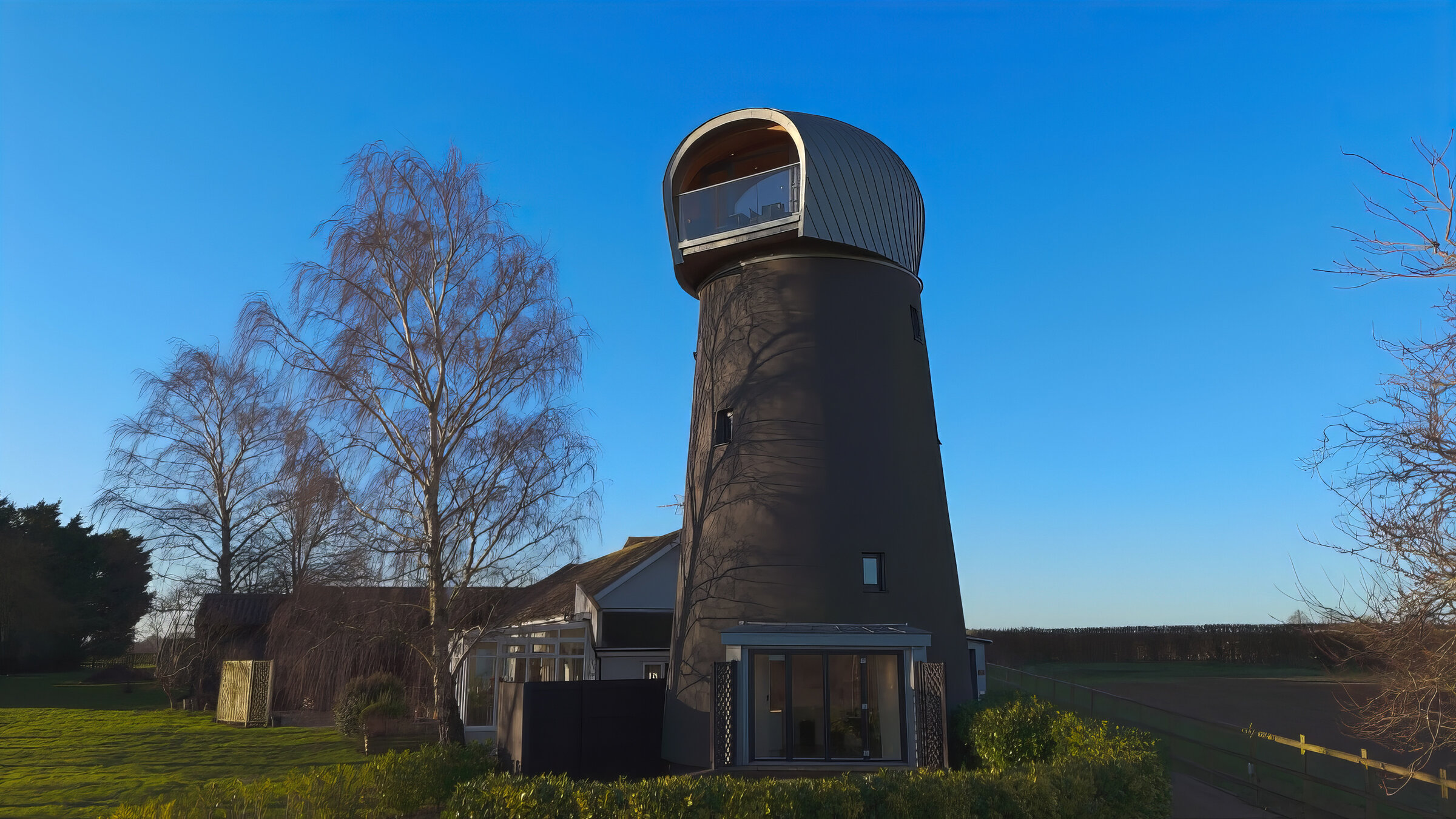 "Die außergewöhnlichsten Hotels - Neue Entdeckungen": Dunkler, runder Turm mit hellem, gewölbtem Aufbau auf der Spitze, umgeben von Bäumen und Wiesen unter blauem Himmel.