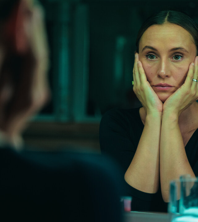 "Eine bessere Welt": Elena (Peri Baumeister) hat ihren Kopf in die Arme gestützt und blickt sich im Spiegel an.