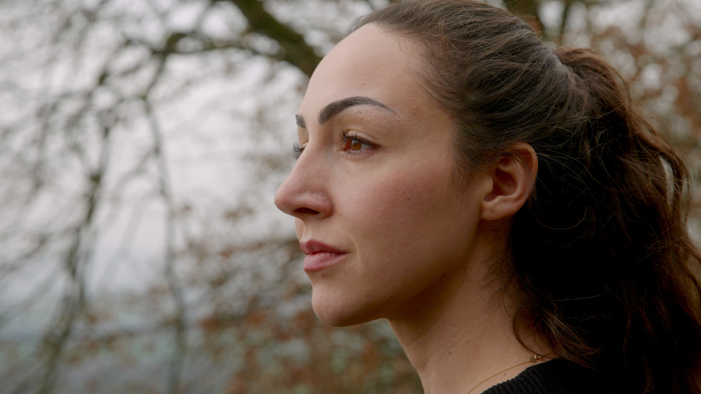 "37°Leben - Suche nach dem Spirit: Life-Coaching": Nahaufnahme: Michi steht im Freien vor einem Baum und schaut zur Seite.