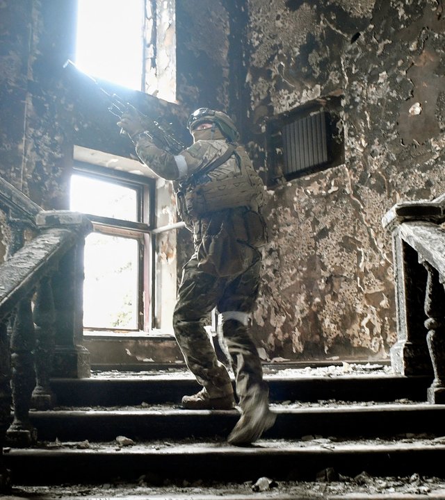 "Tatort Ukraine - Die Russen": Ein russischer Soldat geht mit Maschinengewehr im Anschlag eine Treppe im zerstörten Theater von Mariupol hoch.