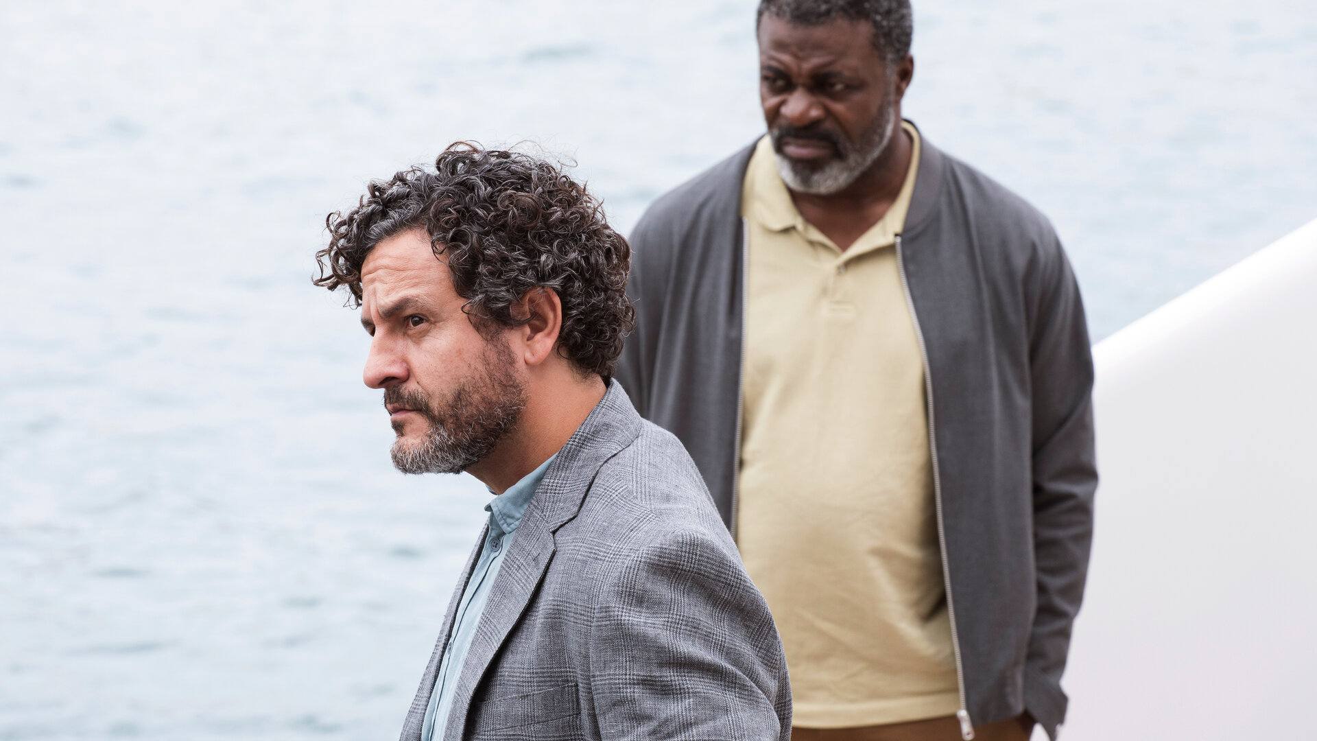 "The Diplomat - Neue Spuren": Inspector Castells (Isak Férriz) und Colin Sutherland (Danny Sapani) stehen auf einem Boot an der Reling und blicken nachdenklich in die Ferne.