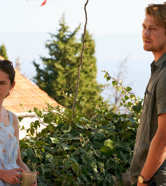 "Conversations with Friends - Am Siedepunkt": Frances (Alison Oliver) und Nick (Joe Alwyn) stehen sich vor einem blühenden Garten gegenüber und schauen aufmerksam zur Seite.