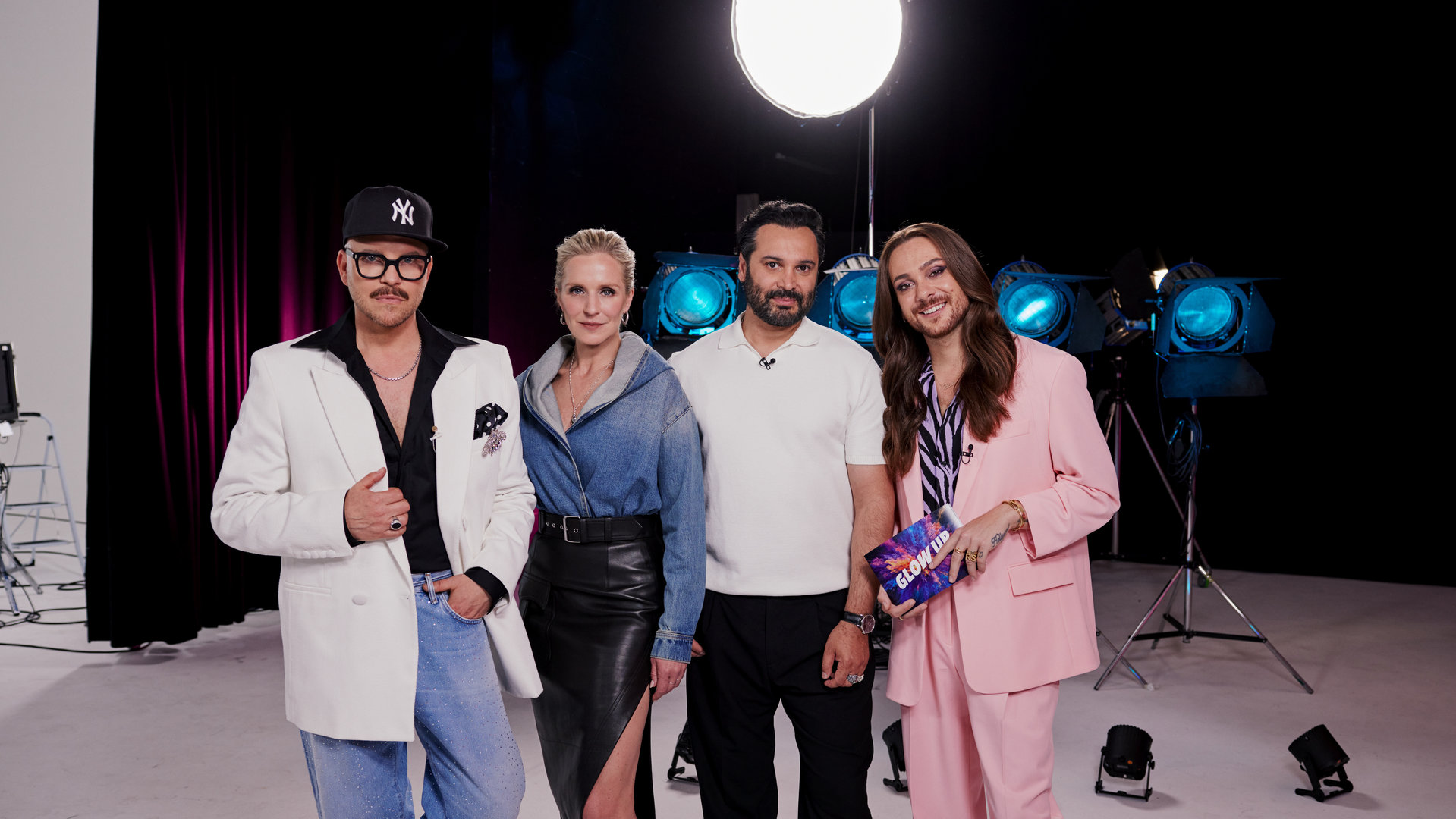 "Glow Up - Deutschlands nächster Make-up-Star": Gruppenfoto von links: Armin Morbach, Loni Baur, Regisseur Reza Norifarahani und Riccardo Simonetti stehen nebeneinander in einem Fotostudio.