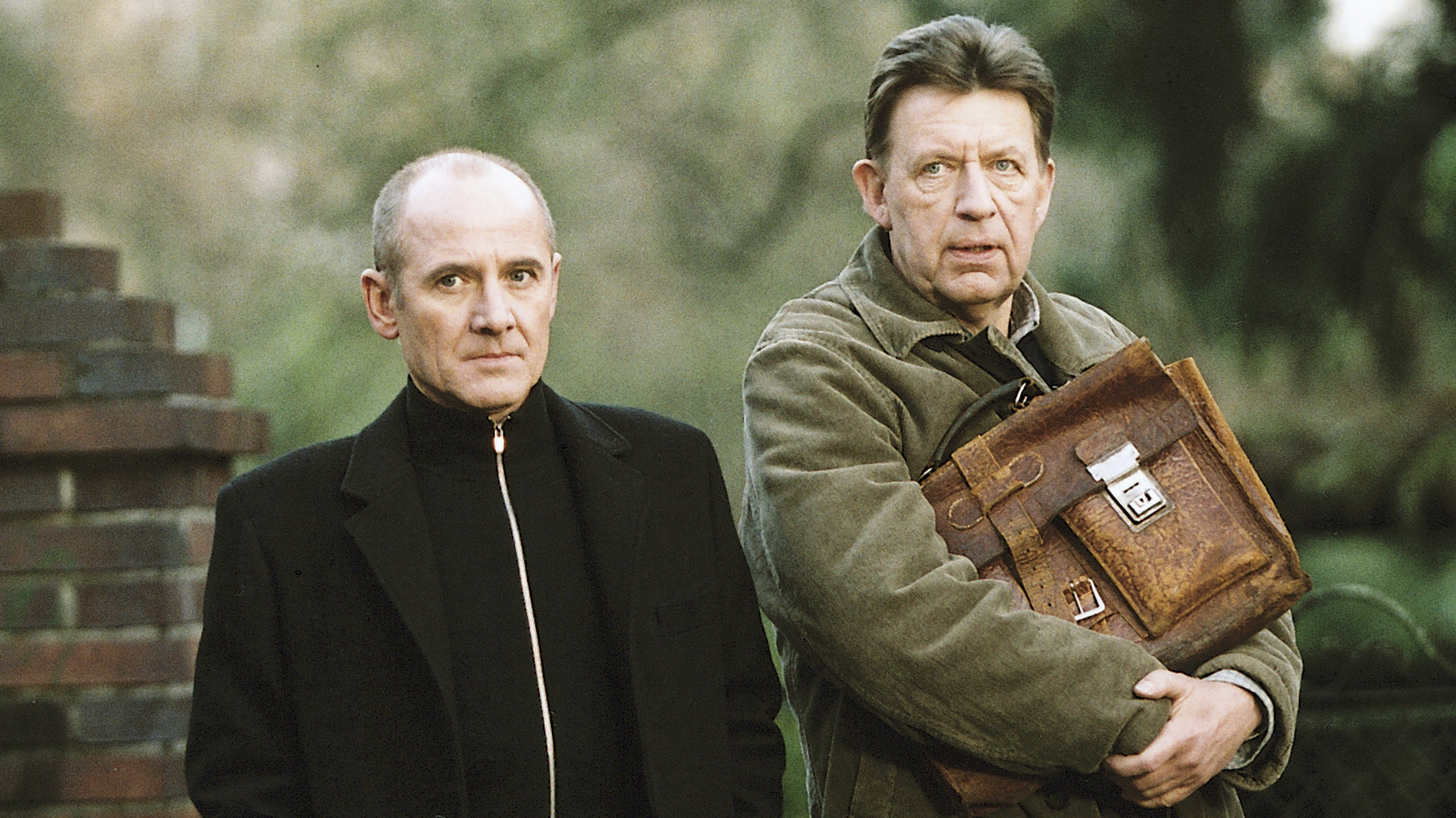 "Der letzte Zeuge - Das rosa Lächeln": Dr. Robert Kolmaar (Ulrich Mühe) und Kommissar Joe Hoffer (Jörg Gudzuhn) stehen nebeneinander und schauen ungläubig in eine Richtung.
