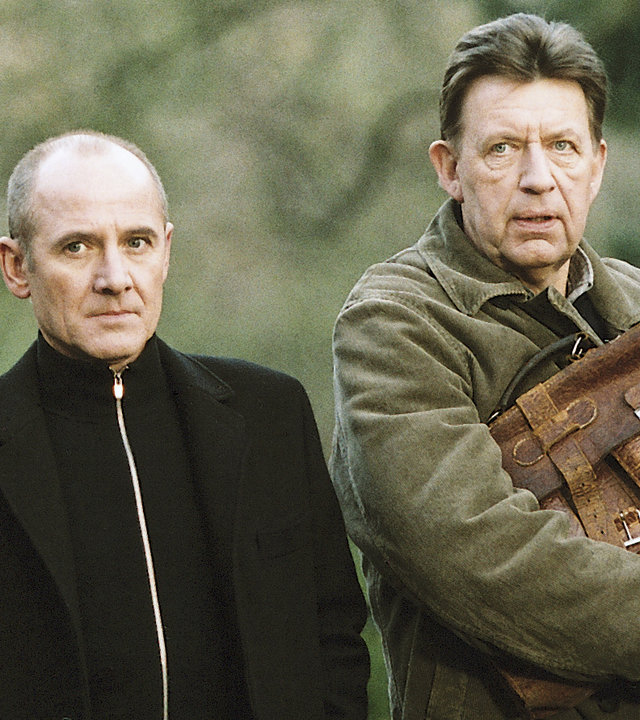 "Der letzte Zeuge - Das rosa Lächeln": Dr. Robert Kolmaar (Ulrich Mühe) und Kommissar Joe Hoffer (Jörg Gudzuhn) stehen nebeneinander und schauen ungläubig in eine Richtung.