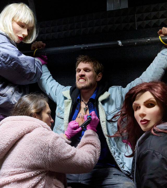 "Stralsund – Ablaufdatum": Der gefesselte Jonathan Theisen (Remo Schulze) wird gegen seinen Willen von zwei Frauen, Nina (Cheyenne Demont) und Anja (Anna Herrmann), festgehalten, die Masken tragen und nicht zu identifizieren sind. Martha (Lo Rivera) kniet vor ihm, hat sein Hemd geöffnet und ist dabei ihn zu tätowieren.