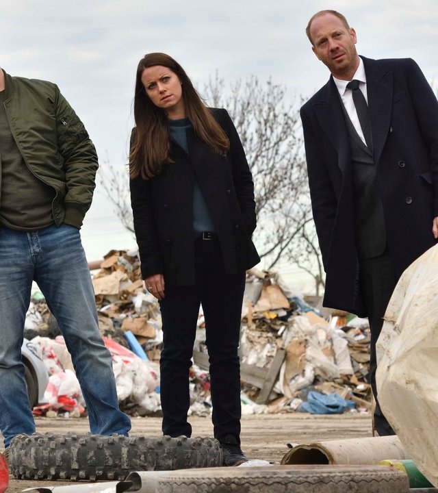 "Herr und Frau Bulle – Abfall": Yvonne (Alice Dwyer), Heiko (Johann von Bülow), und Kevin (Tim Kalkhof) stehen in einer Reihe auf einer Mülldeponie und neigen sich alle nach links.