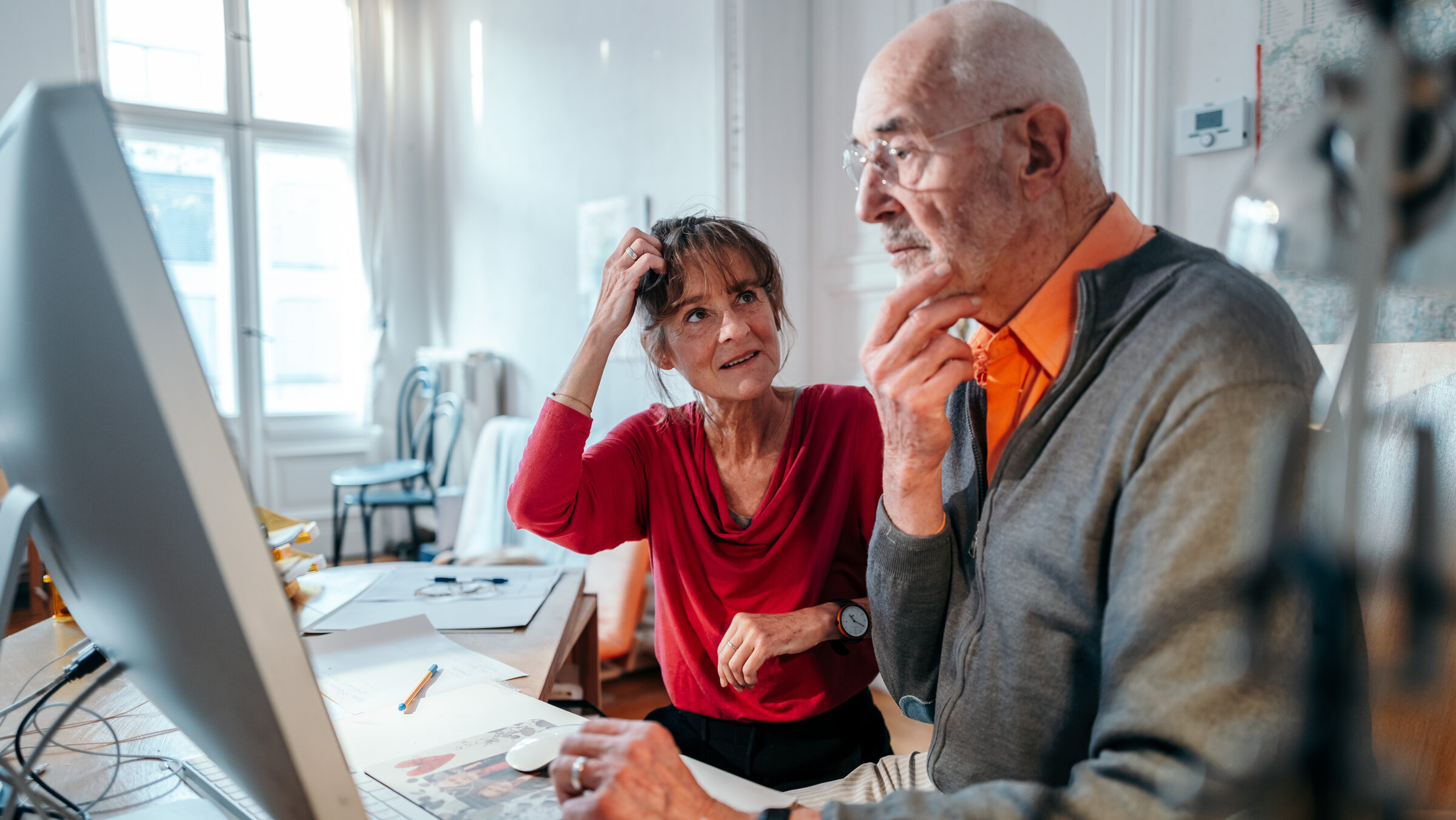 "Digital abgehängt": Dieter und Sabine sitzen an ihrem Schreibtisch in ihrer Wohnung. Sabine schaut zu Dieter, der auf den Bildschirm ihres Computers blickt.