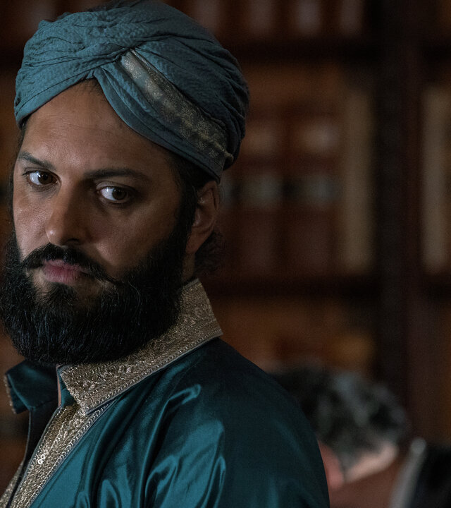 "Nautilus - Die Aktionäre": Nemo (Shazad Latif) steht in einem Raum vor einem Bücherregal. Er trägt elegante indische Kleidung und einen Dastar als Kopfbedeckung.