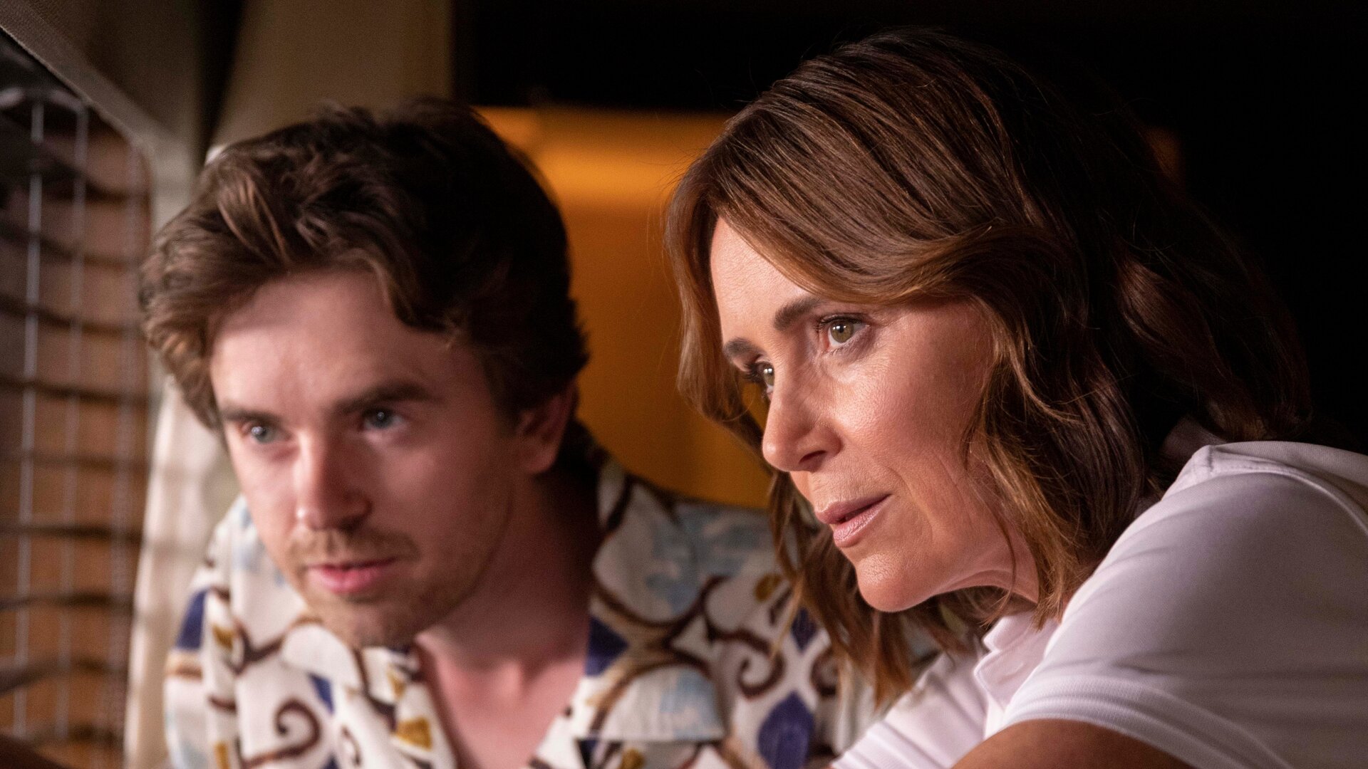 "The Assassin - Eine multifunktionale Käsegabel": Edward (Freddie Highmore) und Julie (Keeley Hawes) stehen in einem Raum nebeneinander vor einem Fenster, das teilweise mit einer Jalousie verhängt ist.