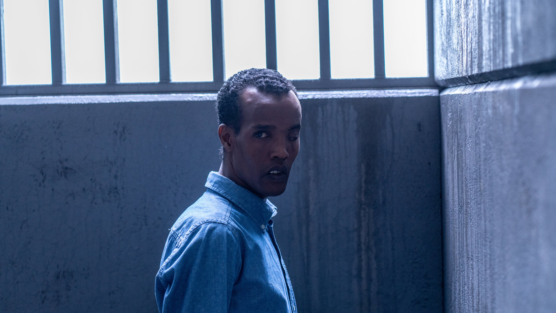 "Detective No. 24 - Abhängig": Ibraahin (Nasir Farah Dhagole) steht in einer Gefängniszelle vor einem vergitterten Fenster.
