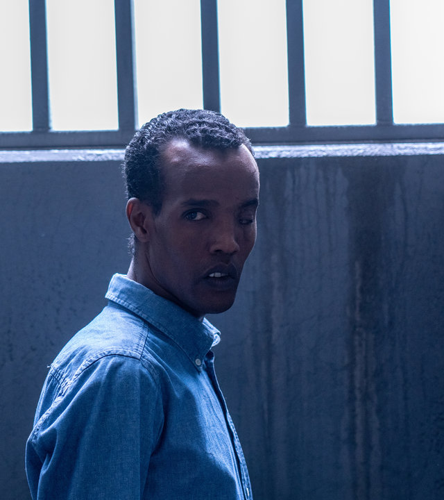 "Detective No. 24 - Abhängig": Ibraahin (Nasir Farah Dhagole) steht in einer Gefängniszelle vor einem vergitterten Fenster.