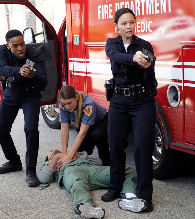 "The Rookie - Skrupellos": Jackson West (Titus Makin Jr.) und Lucy Chen (Melissa O'Neil) zielen mit ihren Waffen zur Seite. Auf dem Boden liegt ein verletzter Mann. Eine weitere Beamtin (Komparsin) gibt ihm eine Herzdruckmassage.