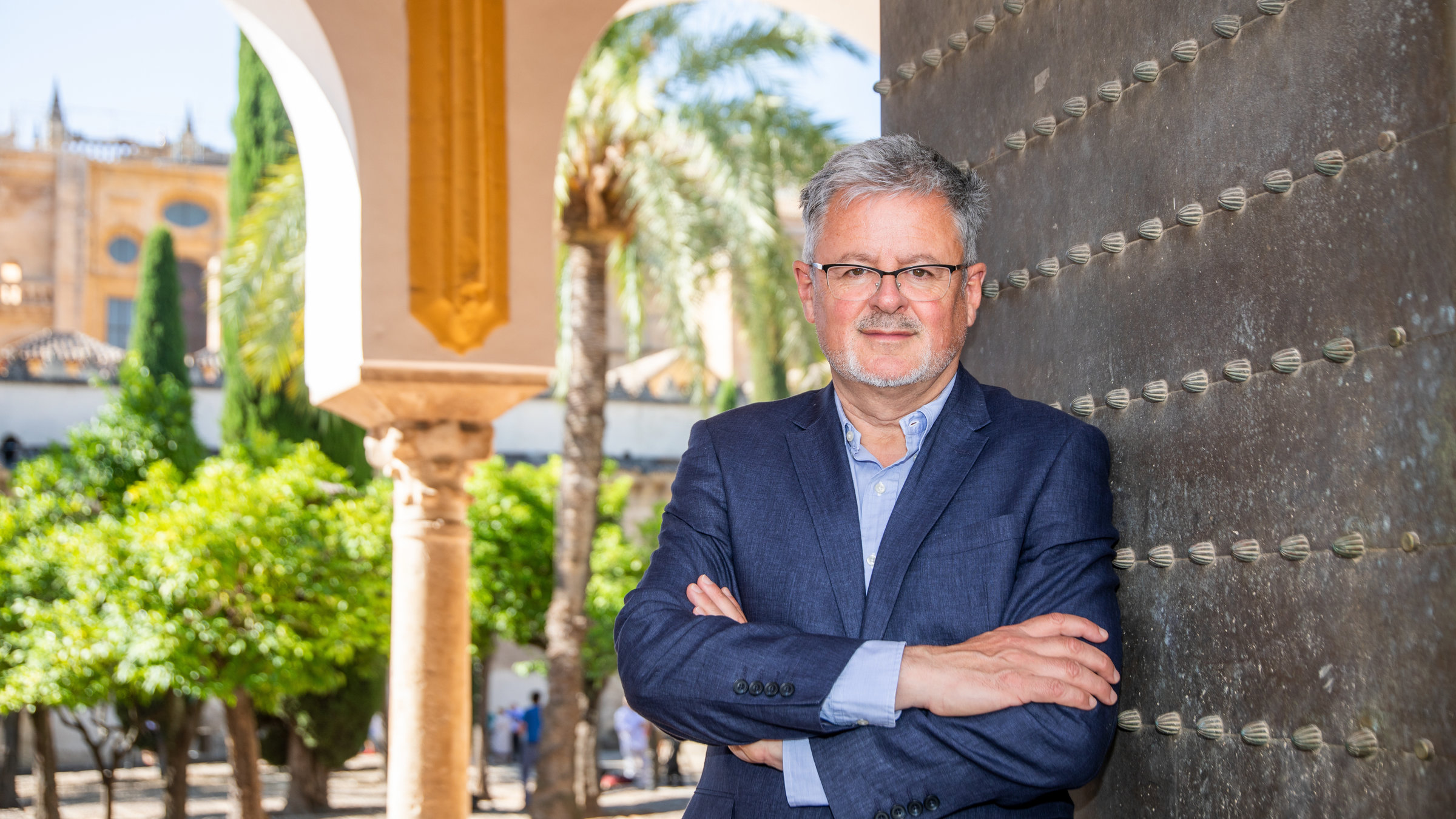 "Terra X: Welten-Saga II - Die Schätze Südeuropas": Moderator Christopher Clark lehnt im blauen Jackett an der Eingangstür zur Mezquita in Cordoba.