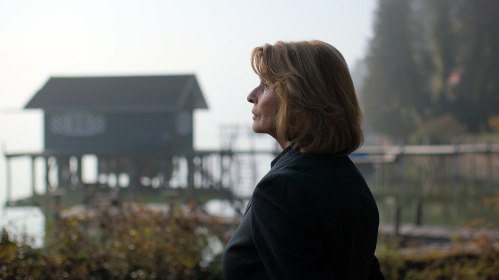 "Unter Verdacht - Evas letzter Gang": Kommissarin Prohacek (Senta Berger) steht an einem See und blickt in die Ferne. Rechts von ihr ein Steg mit einem kleinen Bootshäuschen.