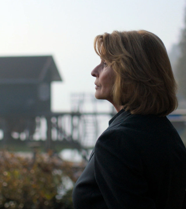 "Unter Verdacht - Evas letzter Gang": Kommissarin Prohacek (Senta Berger) steht an einem See und blickt in die Ferne. Rechts von ihr ein Steg mit einem kleinen Bootshäuschen.