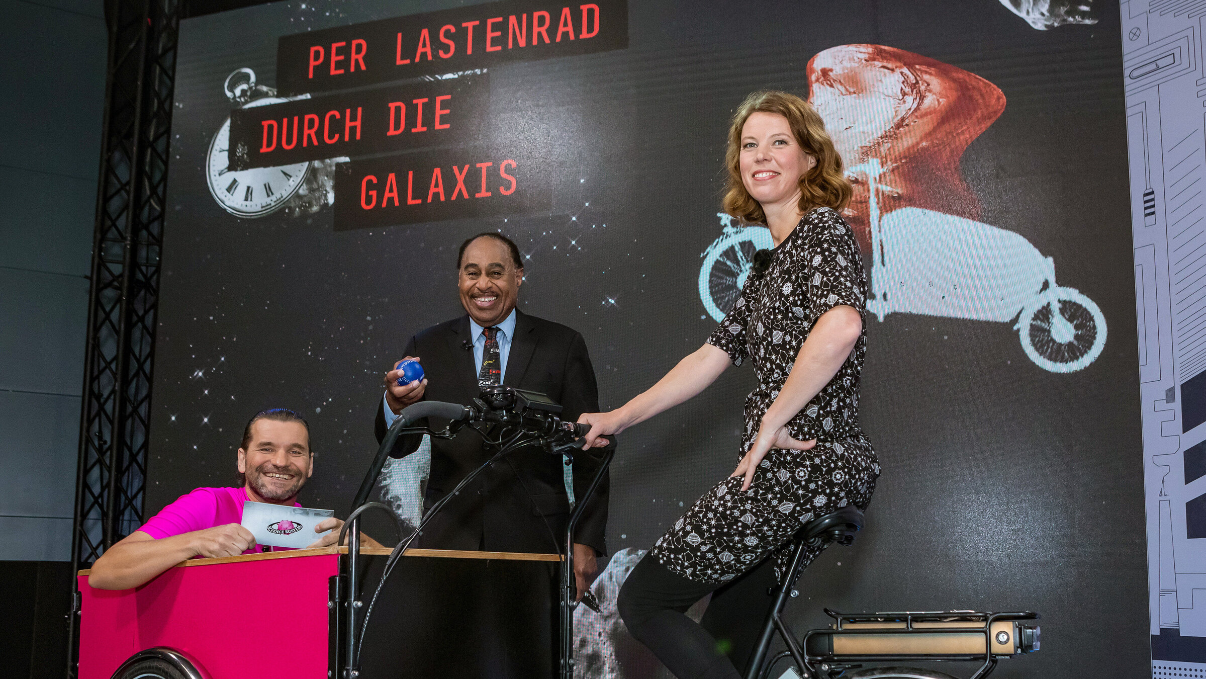 "Science Busters - Wer nichts weiß,muss alles glauben - Per Lastenrad durch die Galaxis": Martin Puntigam, Prof. Dr. Ronald Mallett (Physik), Dr. Ruth Grützbauch (Astronomin).