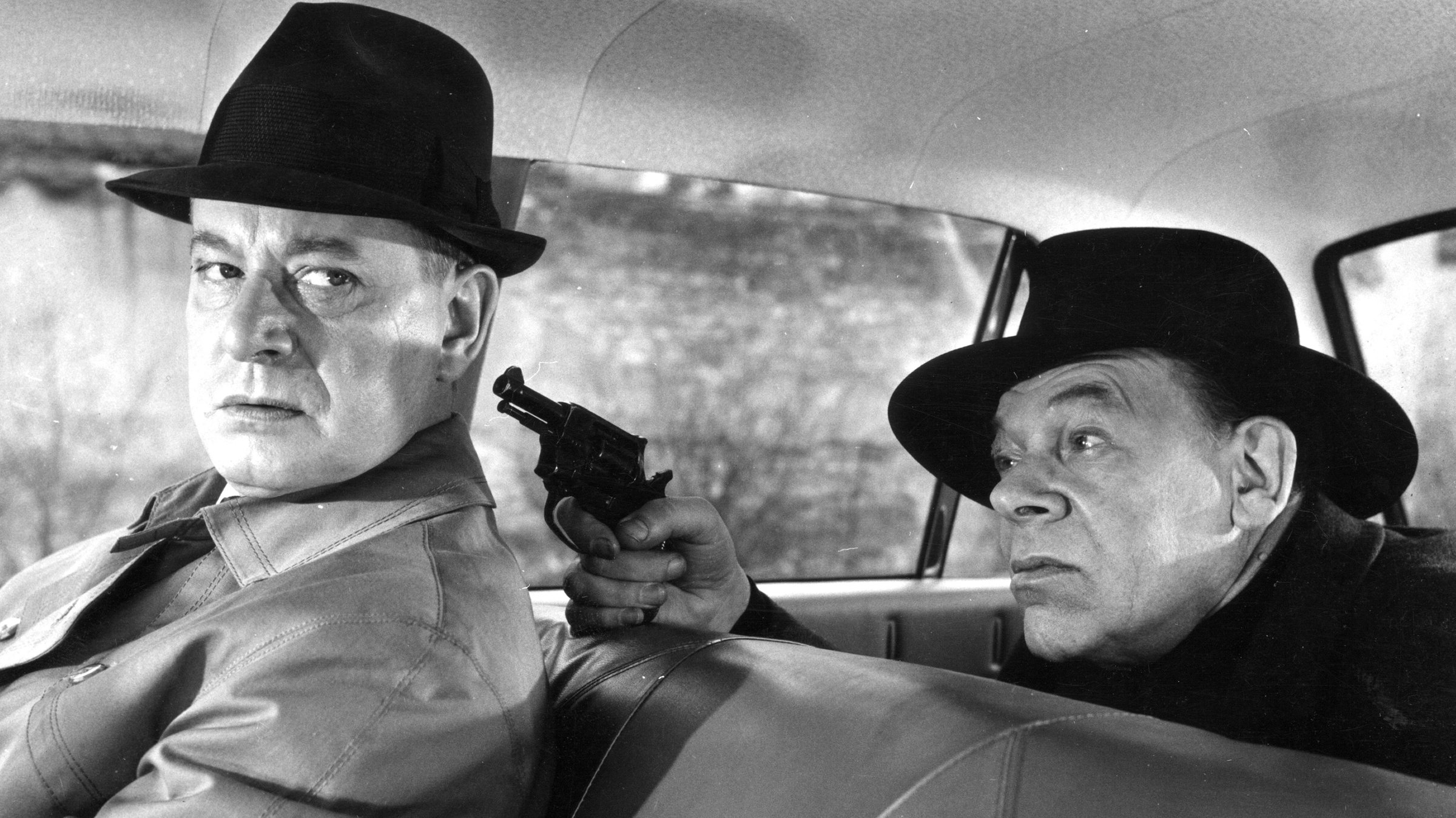 "Das Phantom von Soho": Hugh Patton (Dieter Borsche) sitzt in einem Auto und wird von der Rückbank aus von "Leberfleck" (Otto Waldis) mit einer Pistole bedroht.