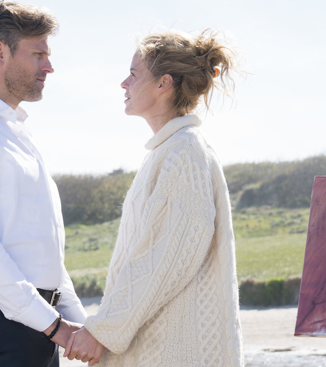 "Cecelia Ahern - Dich zu lieben": Mark (Jens Atzorn) und Claire (Jessica Ginkel) stehen Händchen haltend an einem Sandstrand und sehen sich an. Das Porträt von Mark steht auf einer Staffelei neben ihnen. Im Hintergrund sind Dünen zu erkennen.
