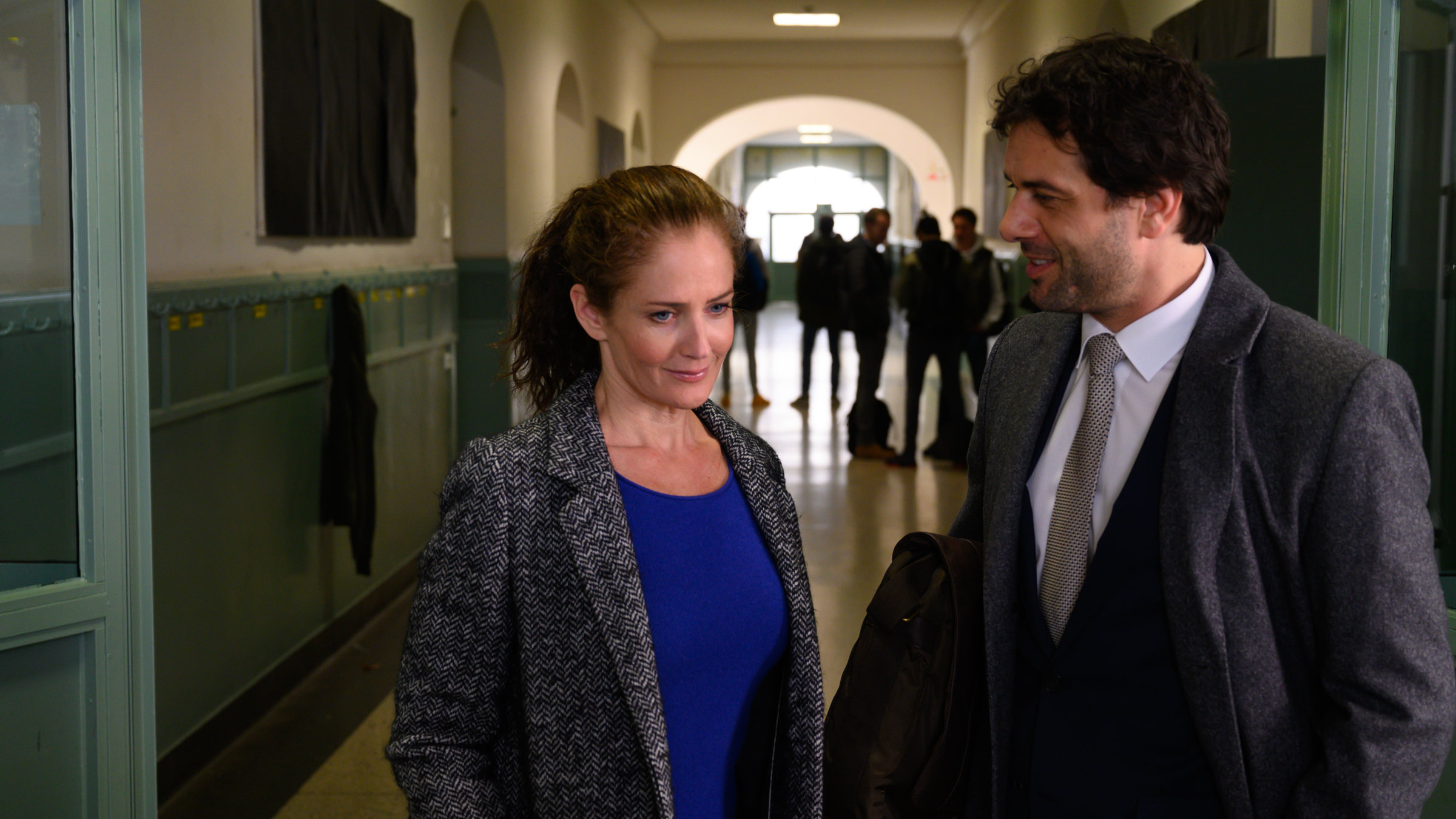 "SOKO Stuttgart - Abi-Krieg": Selma Kirsch (Yve Burbach) unterhält sich mit Simon Baum (Kai Schumann) im Schulflur des Lämmle-Gymnasiums. Im Hintergrund steht eine Gruppe Schüler.