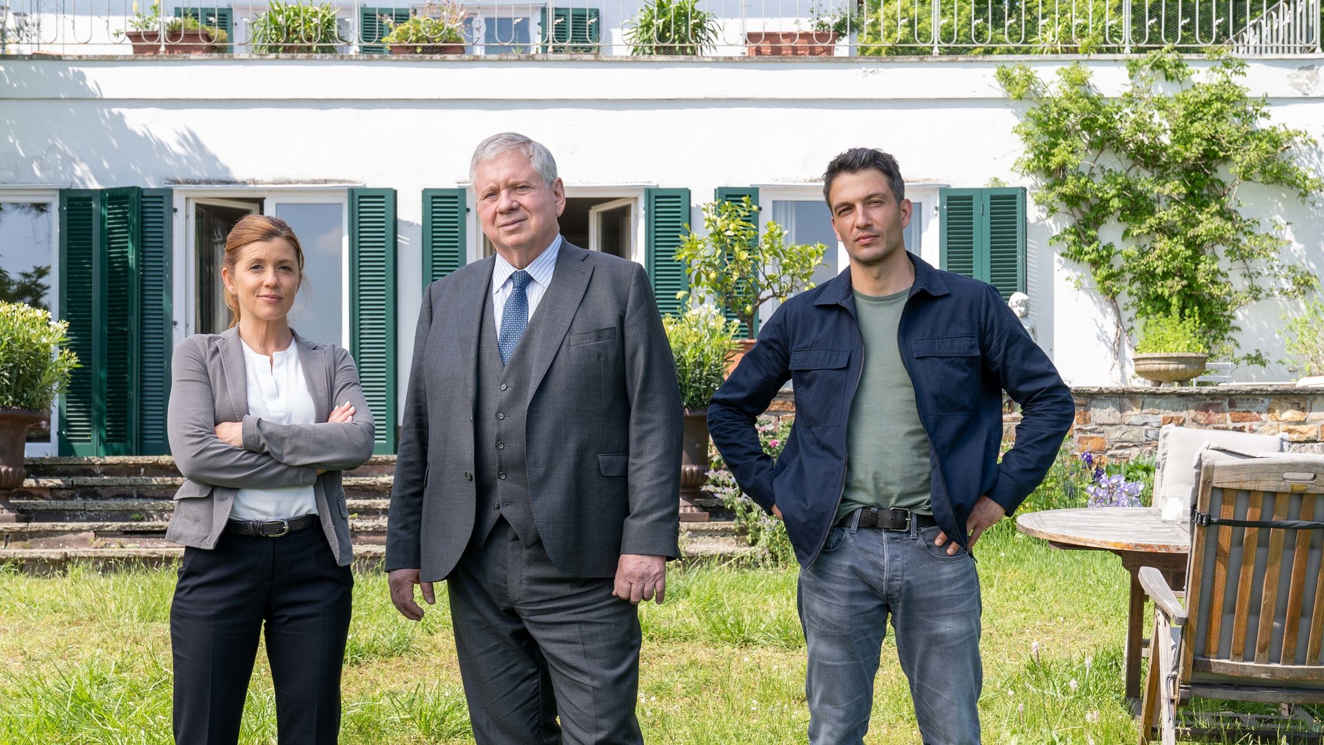 "Der Staatsanwalt - Tod eines Maklers": Hauptkommissarin Kerstin Klar (Fiona Coors), Oberstaatsanwalt Bernd Reuther (Rainer Hunold) und Oberkommissar Max Fischer (Max Hemmersdorfer) stehen auf einer Wiese vor einer Villa. Sie blicken zufrieden in die Kamera.