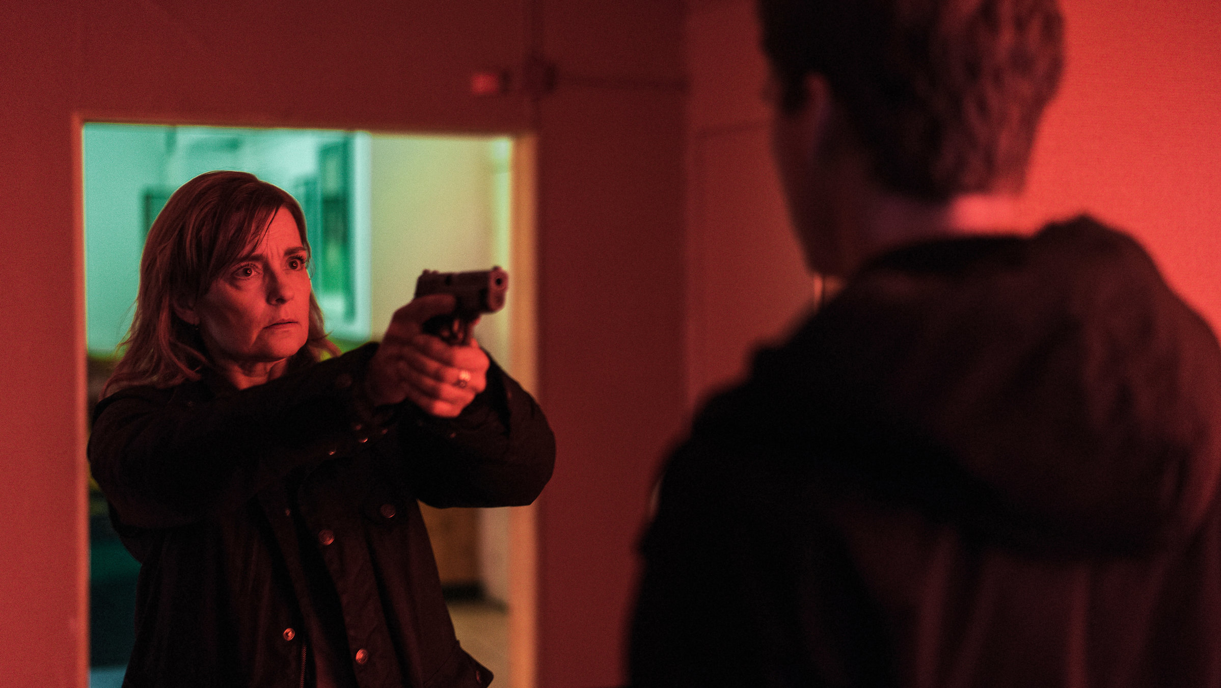 "Hanna Svensson - Blutsbande": Hanna (Marie Richardson) steht in einem Raum mit vorgehaltener Waffe vor ihrem Sohn Christian (Adam Pålsson). Sie macht einen überraschten Gesichtsausdruck.