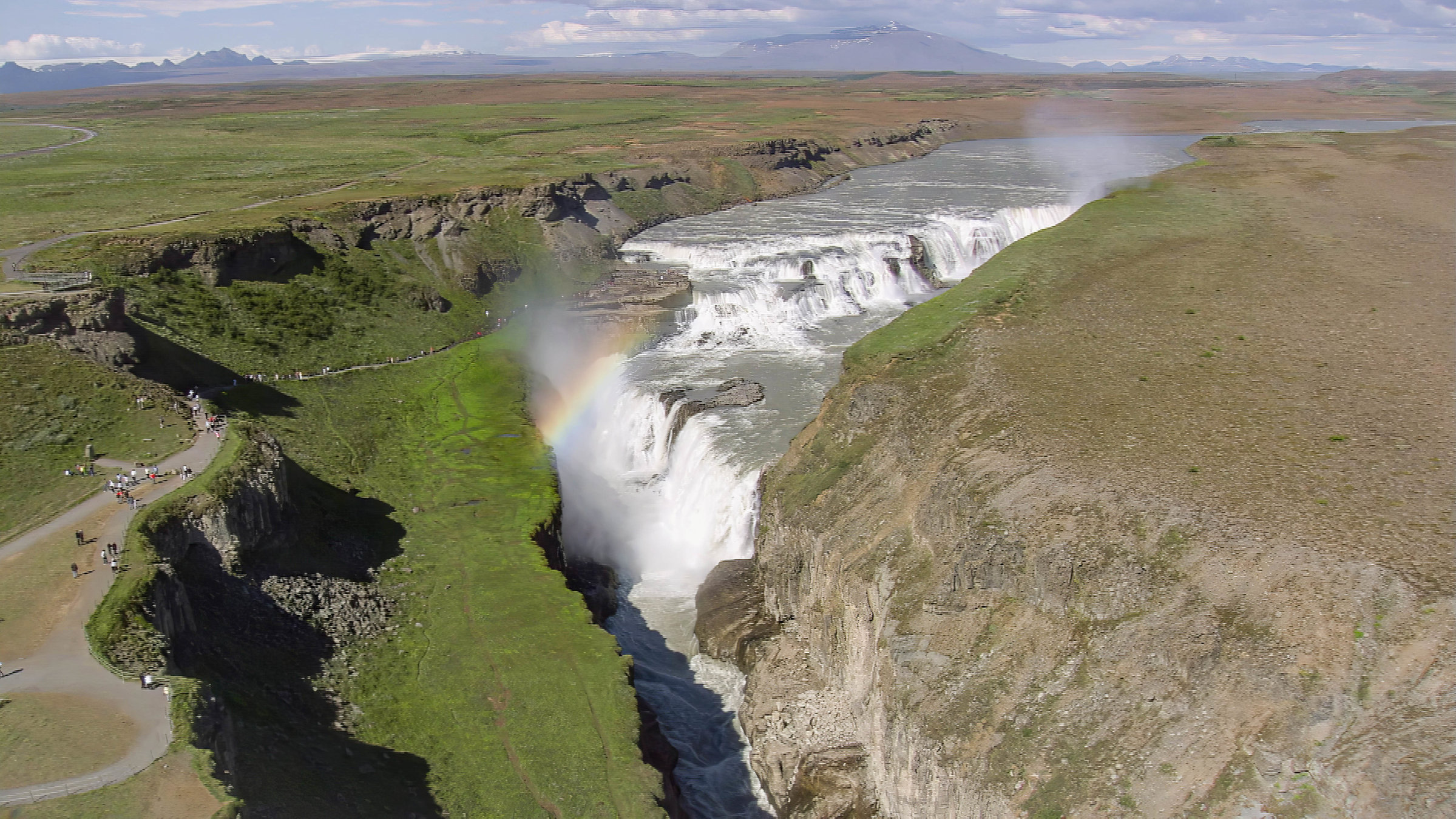 "Island von oben": Luftaufnahme eines Wasserfalls, dessen Wasser in eine tiefe Schlucht fließt.