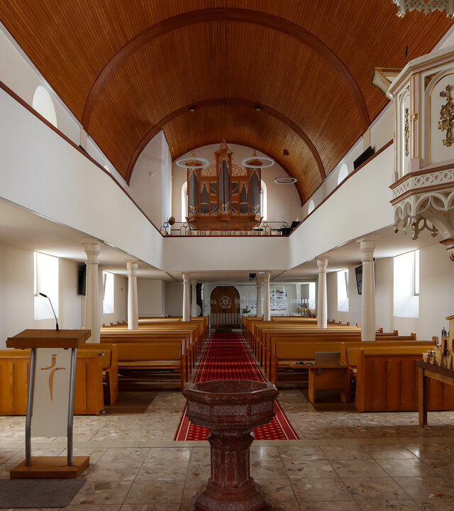 "Evangelischer Gottesdienst - Ja, ich bin getauft!": Innenansicht der Evangelischen Kirche im oberösterreichischen Rutzenmoos. In der vorderen Mitte steht das alte Taufbecken, an der Seite befindet sich die elfenbeinweiße, goldverzierte Kanzel. Der Blick reicht durch das Kirchenschiff bis hinter zum Altar und der sich darüber befindenden Orgel. Kirchgestühl und Decke sind schlicht in hellem Holz gehalten.