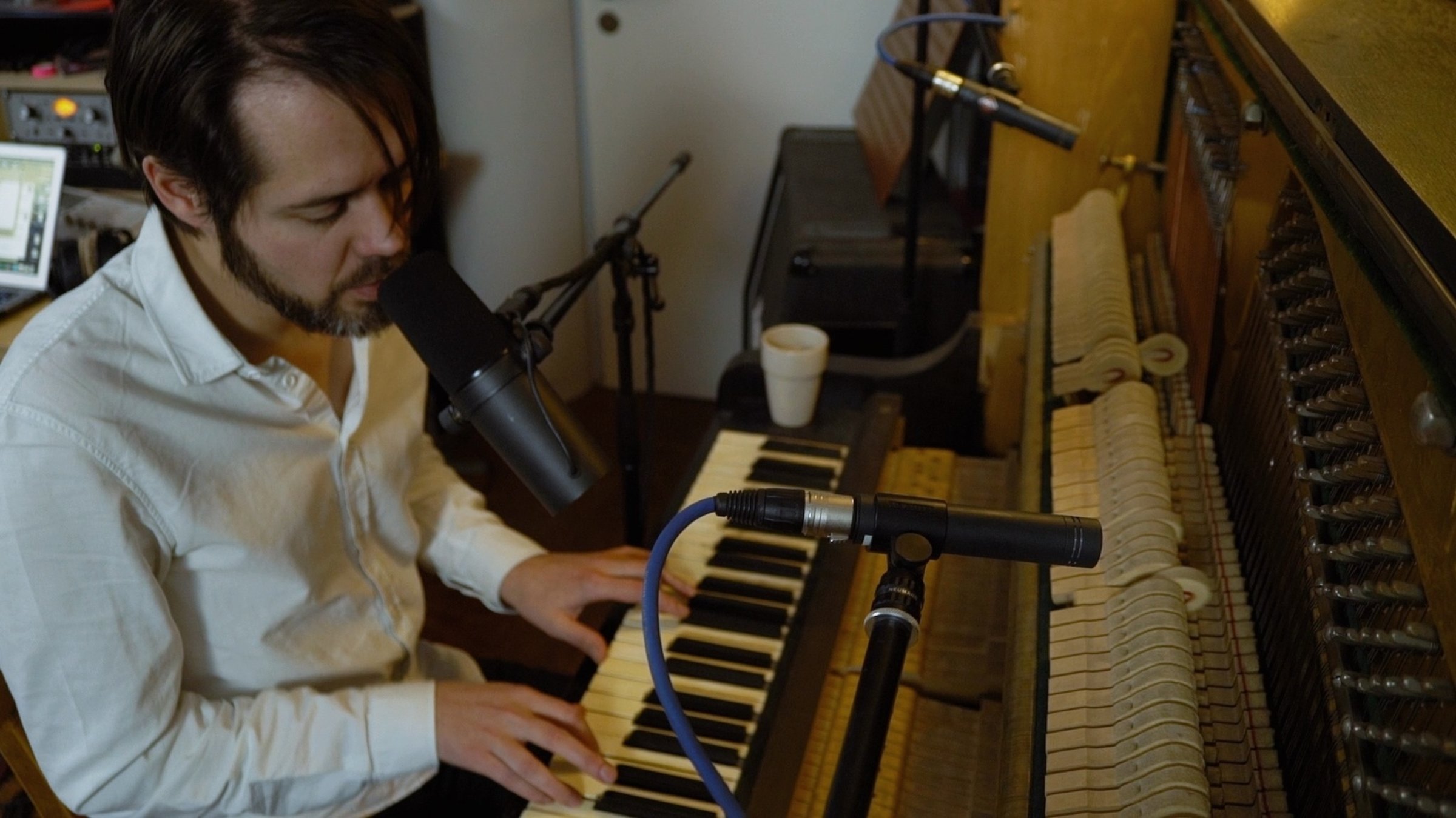 "Wie ein Fremder - Eine deutsche Popmusik-Geschichte - Change": Nahaufnahme eines jungen, bärtigen Mannes, der Klavier spielt und mit geschlossenen Augen in ein Mikrophon singt.