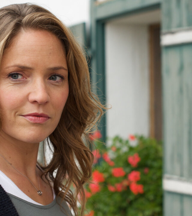 "Lena Lorenz - Ein Fall von Liebe": Lena Lorenz (Patricia Aulitzky) steht vor einem Gasthof; ihr Blick strahlt freudige Erwartung aus.