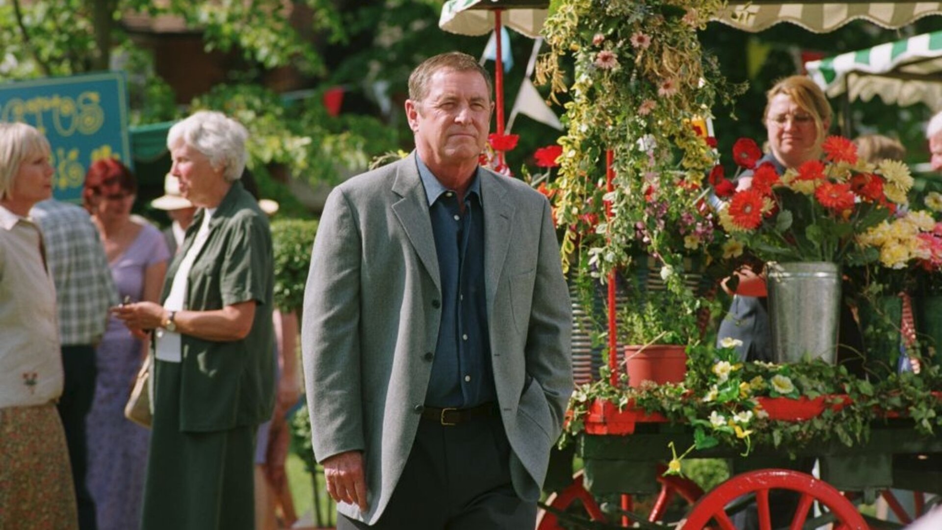 "Inspector Barnaby - Immer wenn der Scherenschleifer ...": DCI Tom Barnaby (John Nettles) steht an einem Blumenwagen. Im Hintergrund sind einige weitere Personen zu erkennen.