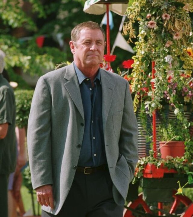 "Inspector Barnaby - Immer wenn der Scherenschleifer ...": DCI Tom Barnaby (John Nettles) steht an einem Blumenwagen. Im Hintergrund sind einige weitere Personen zu erkennen.
