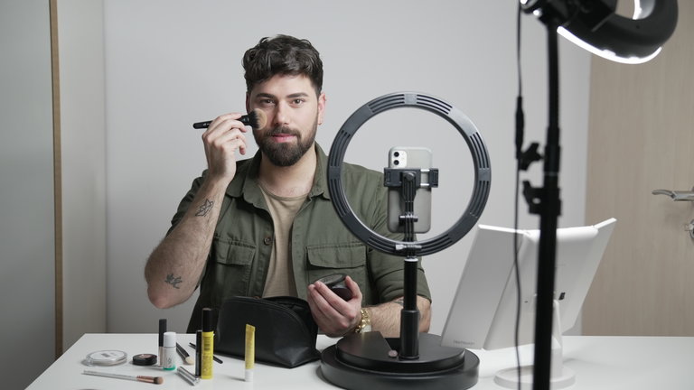"37° Leben: Porenrein - Männer und Schönheit": Davide (32) pudert sich die Wange, während er an einem Tisch sitzt, auf dem Schminkutensilien verteilt sind und filmt sich dabei mit dem Handy.