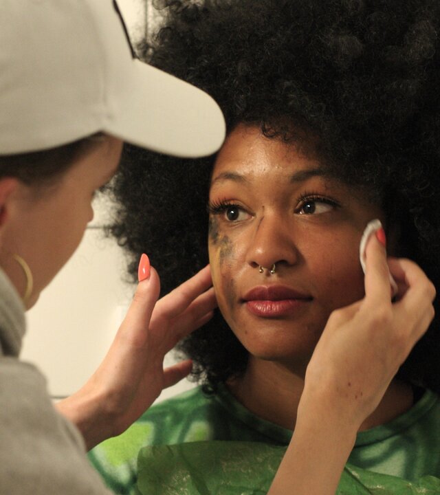 "Hungry - Glitzer": Kimmi (Evelin Schwarz) steht mit dem Rücken zur Kamera und wischt das mit Schminke und Tränen verschmierte Gesicht von Ronnie (Zoe Magdalena) ab. Ronnie schaut Kimmi mit dankbarem Blick an.