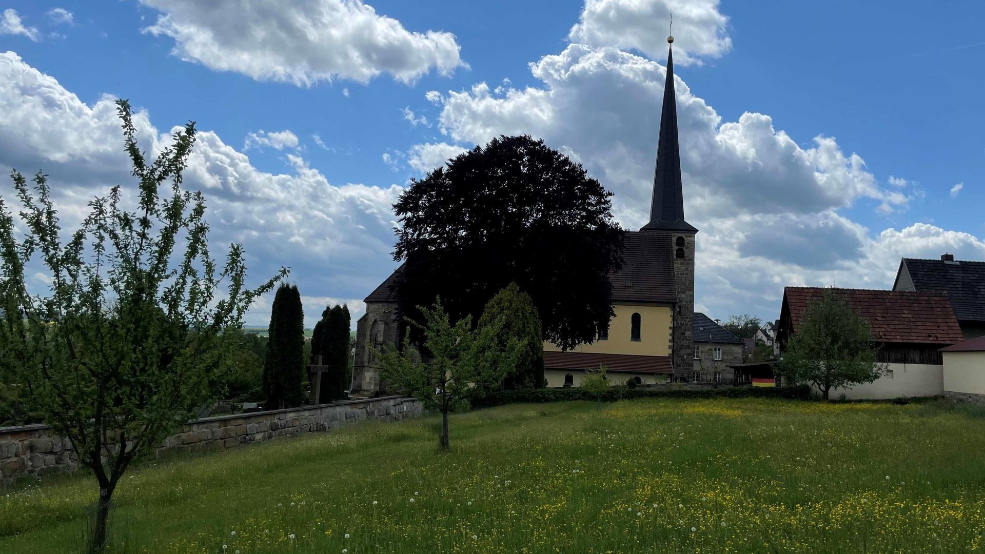 "Katholischer Gottesdienst - Gut versichert - mit Gott": Außenansicht auf die Kirche Heiligste Dreifaltigkeit in Marktgraitz.