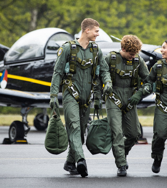 "High-Flyers - Ikarus": Leyla Demir (Sinem Kavus), Guus Walema (Soy Kroon) und Rutger de Man (Josha Stradowski) laufen in ihren Uniformen nebeneinander her. Hinter ihnen steht das Schulungsflugzeug PC-7.