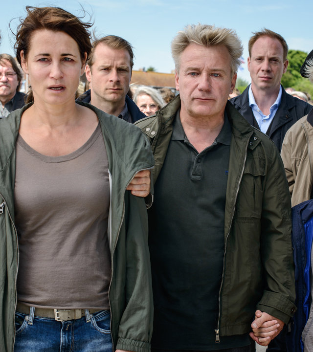"Tod eines Mädchens (1)": Hella Christensen (Barbara Auer), Silke Broder (Anja Kling), Torben Broder (Hinnerk Schönemann), Hermann Broder (Peter Striebeck), Lars von Ahnefeld (Johann von Bülow), Hauke Broder (Jörg Schüttauf) und Charlotte Broder (Lilly Barshy) stehen verzweifelt zusammen und schauen in die gleiche Richtung. Im Hintergrund stehen noch viele weitere Menschen.