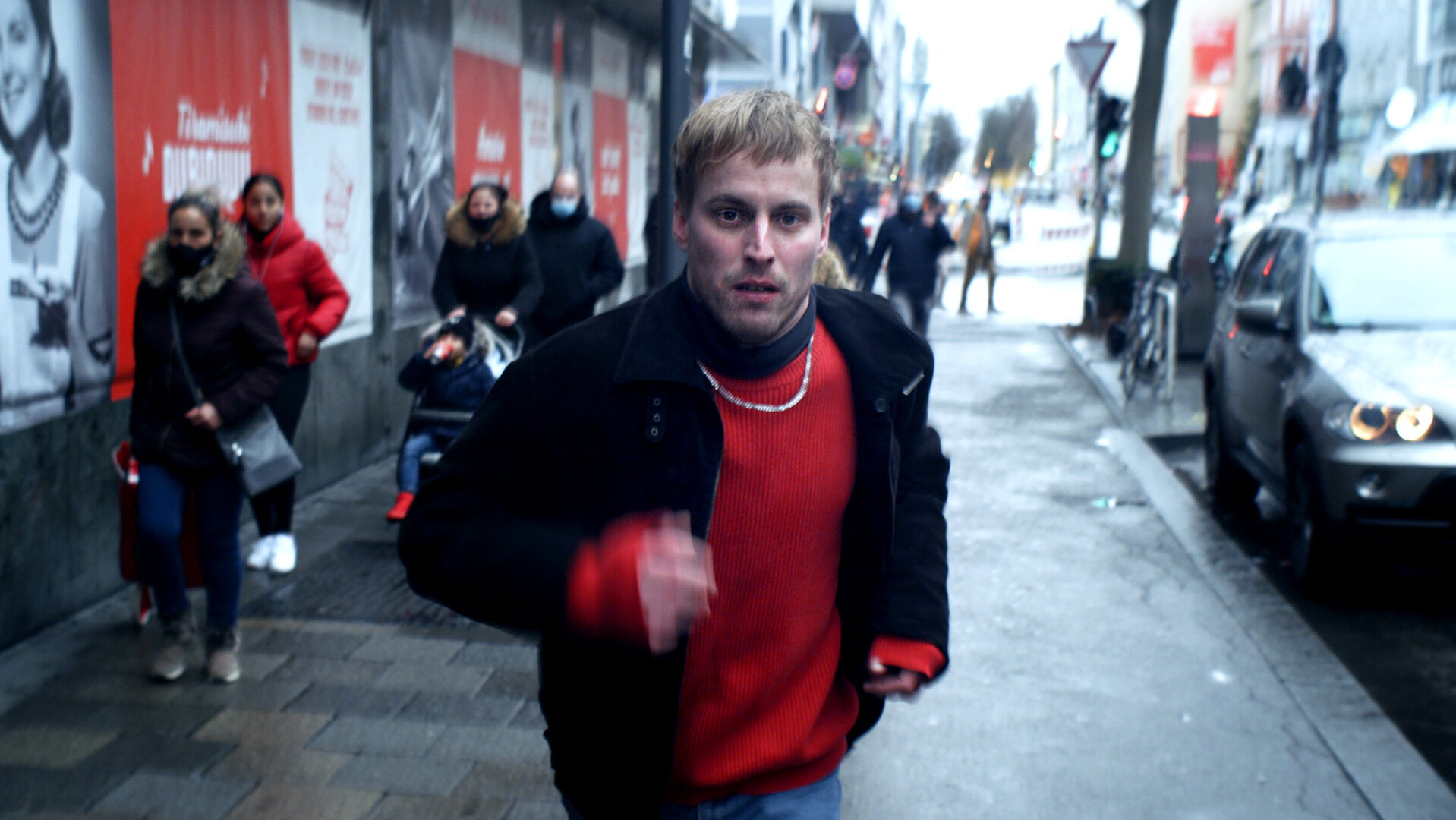 "I AM THE GREATEST - Alles Übel der Welt": Daniel (Christian Erdt) rennt auf einer lebhaften Straße los. Im Hintergrund sieht man viele Passanten.