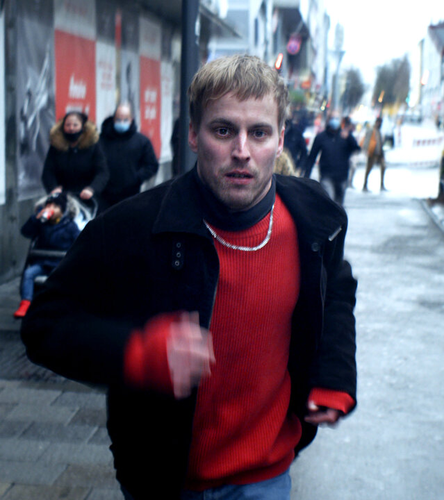 "I AM THE GREATEST - Alles Übel der Welt": Daniel (Christian Erdt) rennt auf einer lebhaften Straße los. Im Hintergrund sieht man viele Passanten.