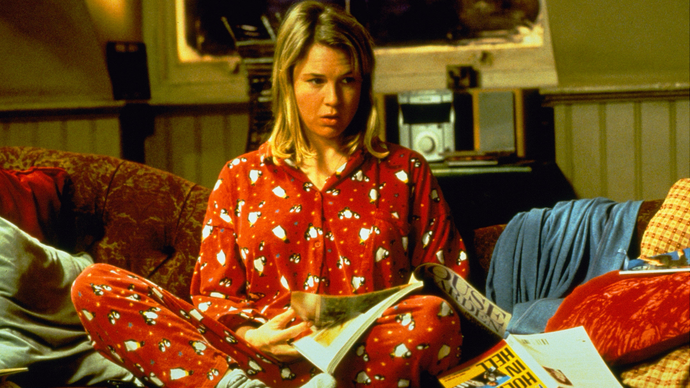 "Bridget Jones - Schokolade zum Frühstück": Bridget Jones (Renée Zellweger) sitzt im Schlafanzug auf dem Sofa und blättert in einer Zeitschrift.