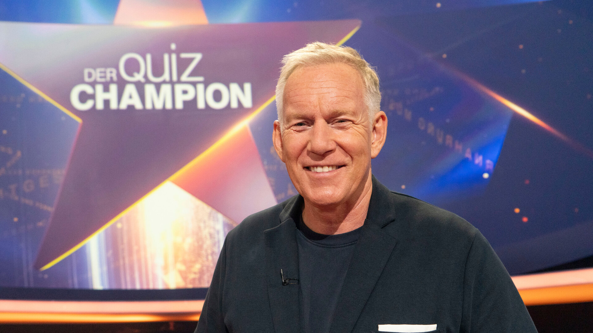"Der Quiz-Champion - Das Spenden-Special": Johannes B. Kerner steht vor Logo im Studio und lacht in die Kamera.