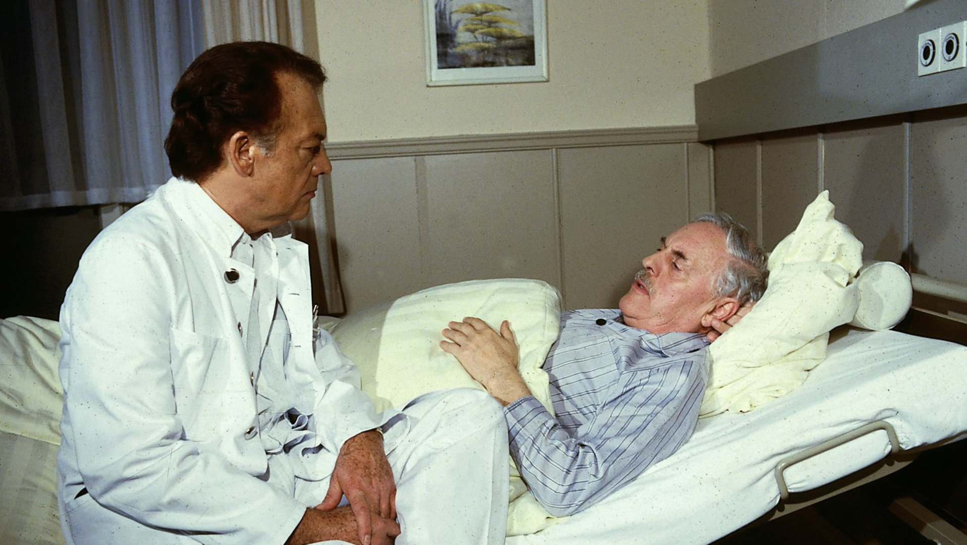 "Die Schwarzwaldklinik - Eine starke Frau": Prof. Brinkmann (Klausjürgen Wussow) sitzt beim Patienten Franz Lempert (Klaus Höhne) am Bett und unterhält sich mit ihm.